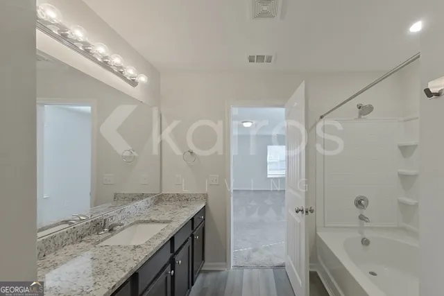 a bathroom with a granite countertop sink a large mirror and shower