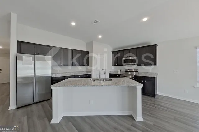 a view of kitchen with stainless steel appliances granite countertop cabinets and wooden floor