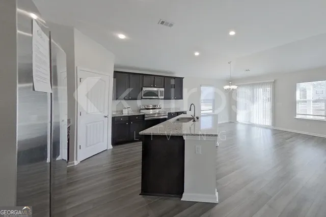 a kitchen with kitchen island stainless steel appliances cabinets and wooden floor