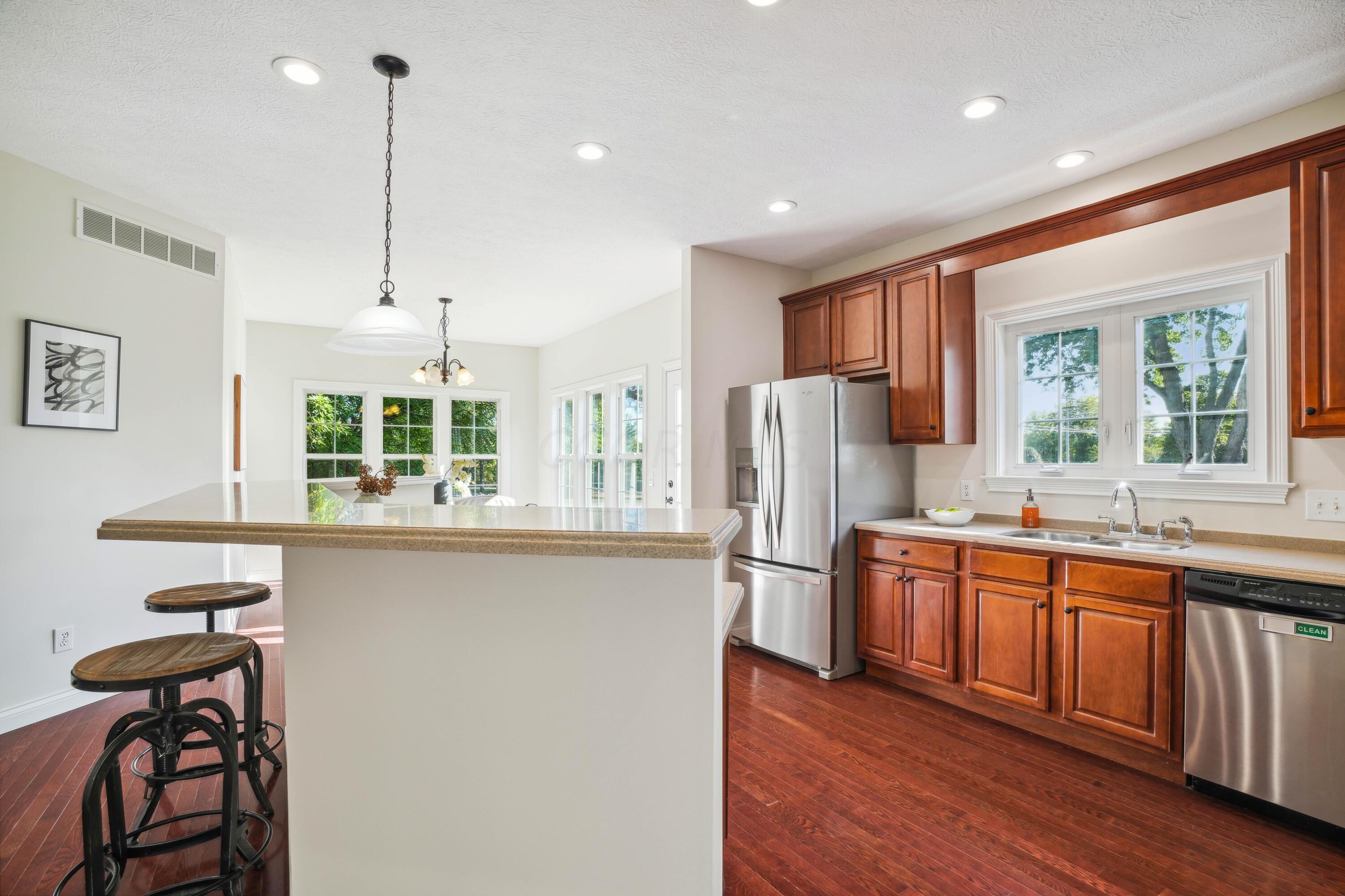 10403 Liberty Road Powell, OH 43065 - Photo 28 of 76 Open Kitchen with countertop seating, NEW SS appliances, Dining Area, Cherry cabinets with custom vent hood, corian countertops and walk-in pantry plus beautiful hardwood floors!