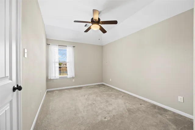 an empty room with windows and fan