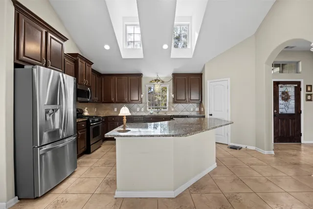 a large kitchen with kitchen island a large counter top stainless steel appliances cabinets and a counter space