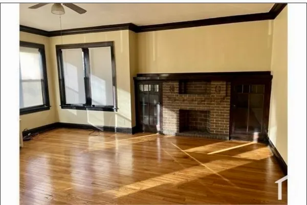 a view of an empty room with wooden floor and a fireplace