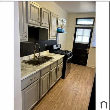 a kitchen with a sink and a stove top oven with wooden floor