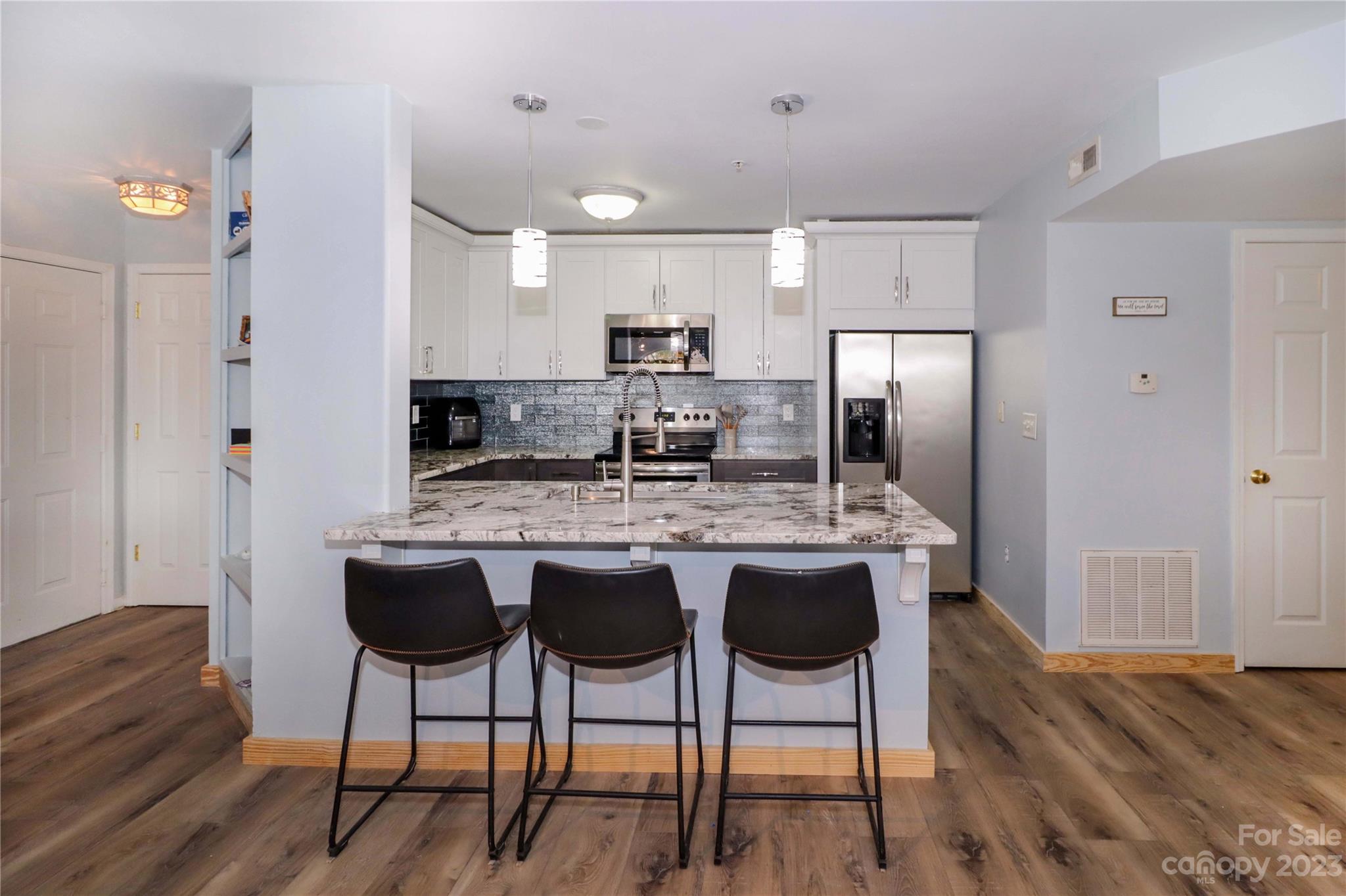 160 James Road, Unit 1D High Point, NC 27265 - Photo 18 of 33 a kitchen with stainless steel appliances granite countertop a stove a refrigerator a sink a dining table and chairs with wooden floor
