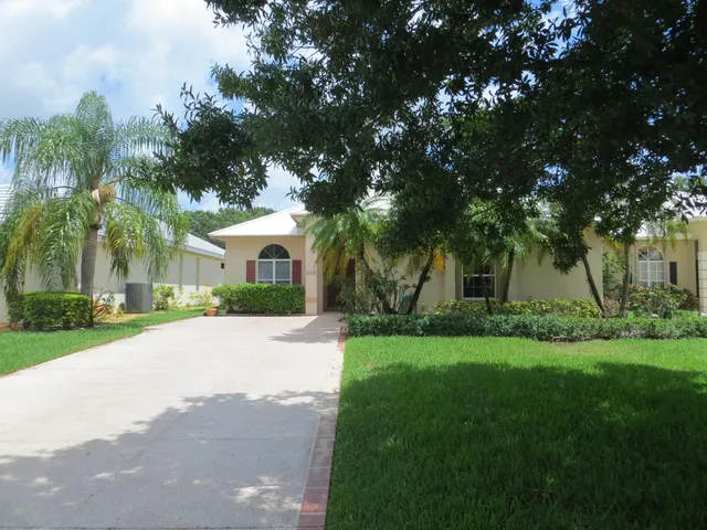 a front view of a house with a garden and trees