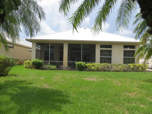 a view of a house with a yard and palm trees