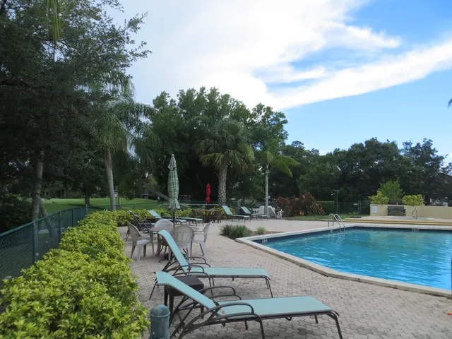 a view of a swimming pool with chairs and a yard