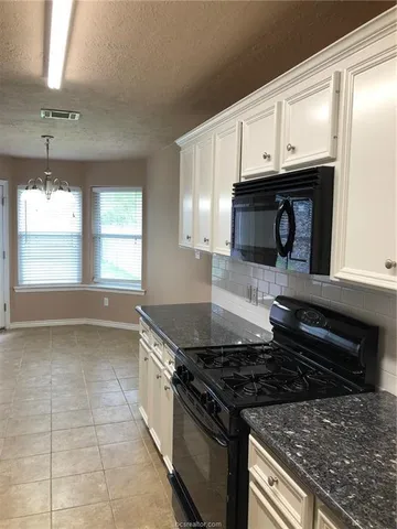 a kitchen with granite countertop a stove and a refrigerator