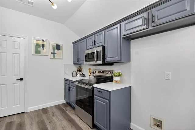 a kitchen with stainless steel appliances a sink dishwasher stove and microwave with wooden floor
