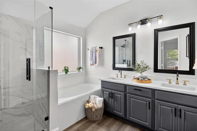 a bathroom with a double vanity sink mirror and bathtub
