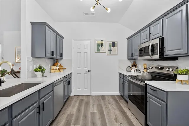 a kitchen with stainless steel appliances granite countertop a stove a sink dishwasher and a refrigerator with wooden cabinets