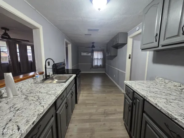 a kitchen with granite countertop cabinets a sink and a wooden floors