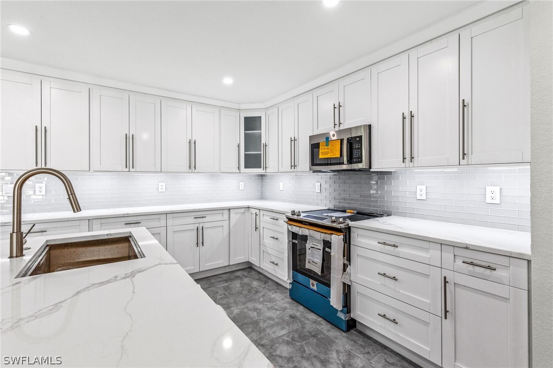 a kitchen with granite countertop white cabinets and stainless steel appliances