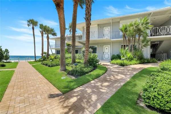 a front view of a house with a yard and potted plants