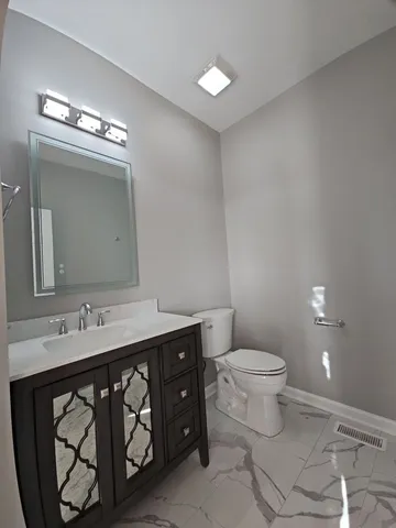 a bathroom with a granite countertop sink a toilet and a mirror