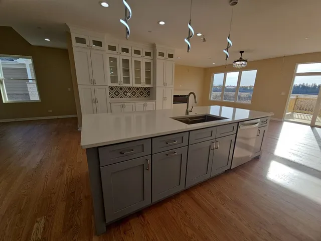 a kitchen with stainless steel appliances granite countertop a sink cabinets and wooden floor