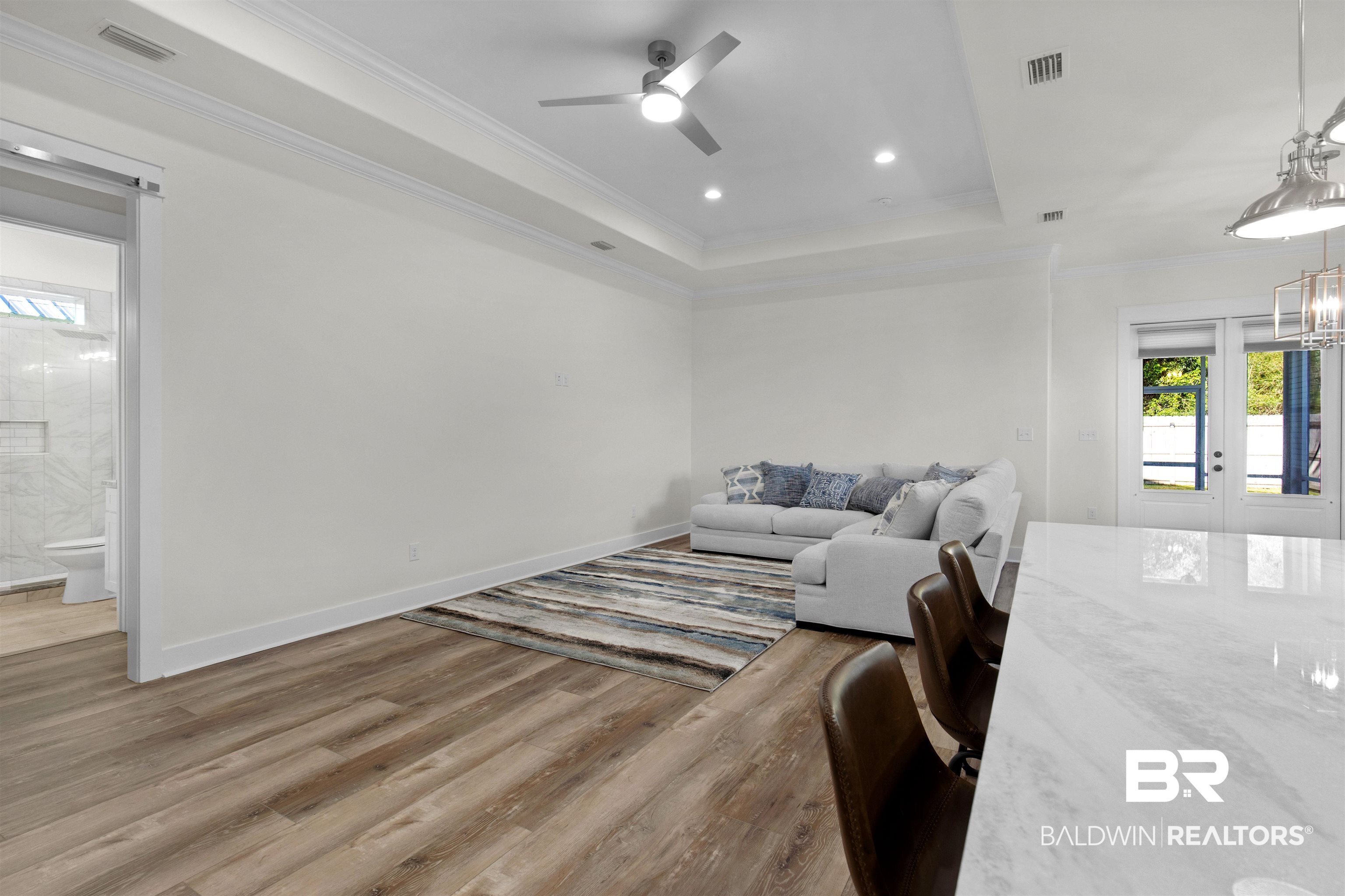 8069 Carmel Circle Foley, AL 36535 - Photo 5 of 23 Living room featuring a tray ceiling, crown molding, wood finished floors, baseboards, and visible vents