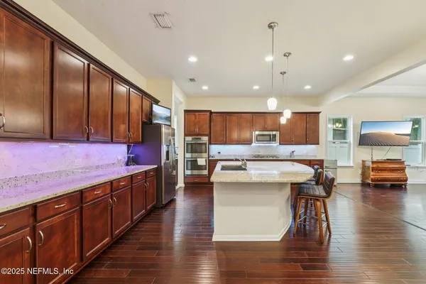 a kitchen with stainless steel appliances kitchen island granite countertop a stove a sink and a refrigerator