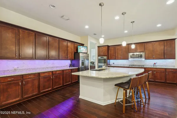 a kitchen with stainless steel appliances kitchen island granite countertop wooden cabinets and sink