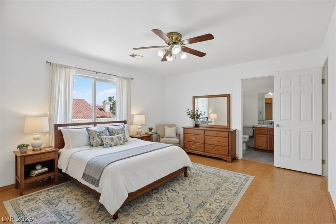 3698 Laughlin Boulevard Laughlin, NV 89029 - Photo 37 of 49 Well-lit primary bedroom featuring durable wood flooring, a ceiling fan, and direct access to a private bathroom.