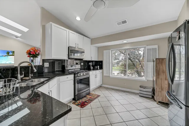 a kitchen with granite countertop a stove a sink and a refrigerator