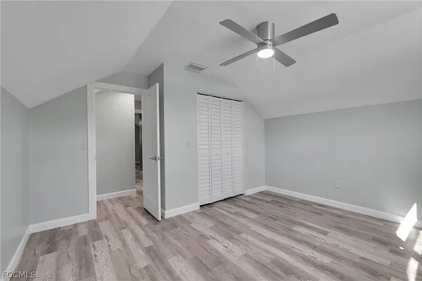 an empty room with wooden floor and ceiling fan