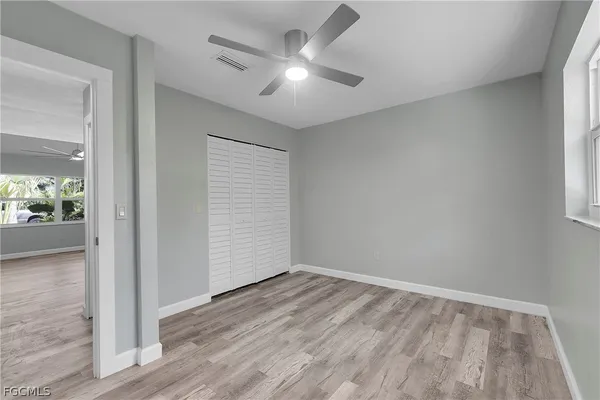 an empty room with wooden floor and a ceiling fan