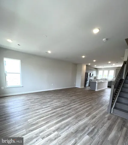 an empty room with wooden floor and staircase