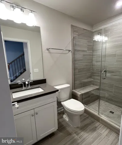 a bathroom with a granite countertop sink a toilet a mirror and shower