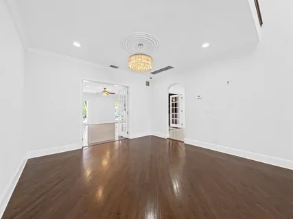 a view of an empty room with wooden floor and a ceiling fan