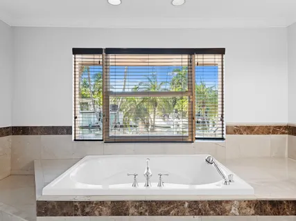 a bathroom with a tub a sink and a large window