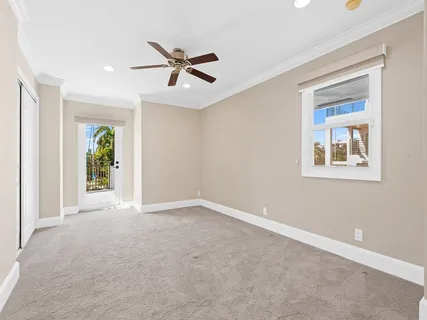an empty room with ceiling fan and windows