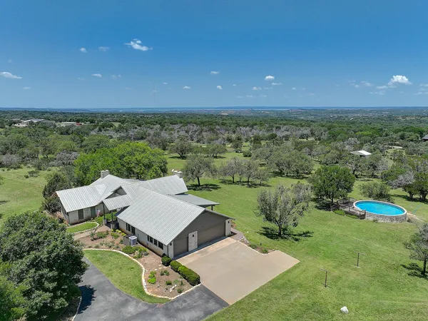 an aerial view of a house with pool big yard and large tree