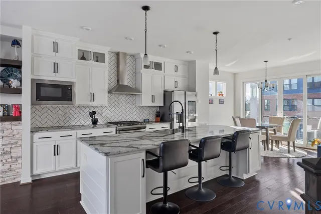 a kitchen with stainless steel appliances granite countertop a stove a sink dishwasher a refrigerator white cabinets and wooden floor