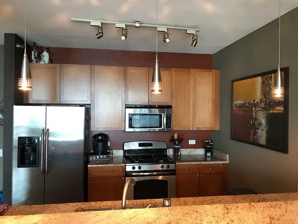a kitchen with stainless steel appliances kitchen island granite countertop a refrigerator and a stove top oven