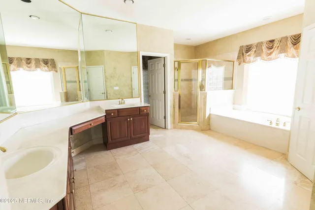 a spacious bathroom with a tub sink shower and mirror