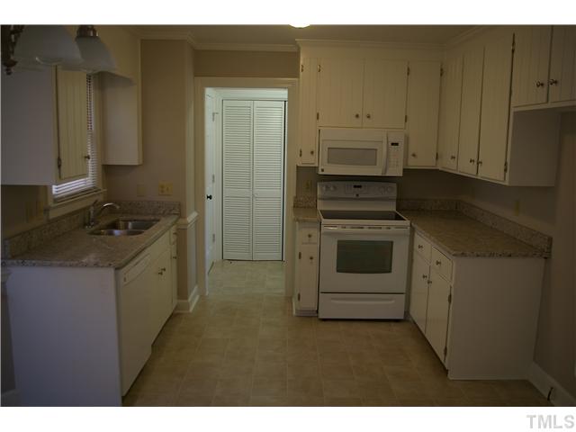 8112 Round Oak Road Raleigh, NC 27616 - Photo 2 of 18 updated kitchen with granite counter tops, new appliances, paint, light fixture, vinyl flooring, cabinet hardware. conveniently located laundry room and 1/2 bath shown in background.