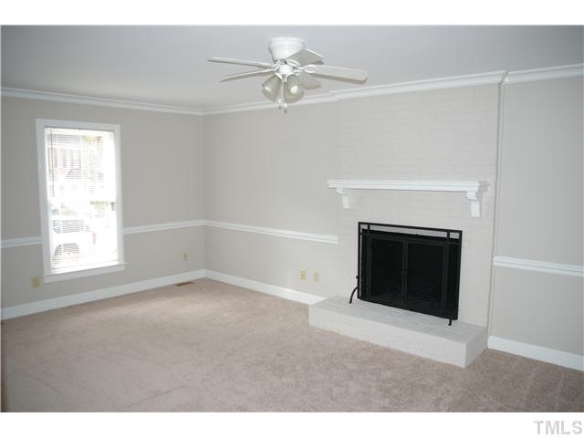 8112 Round Oak Road Raleigh, NC 27616 - Photo 6 of 18 white painted wood base board, chair railing and crown molding on first level. fire place screen over wood burning fireplace.