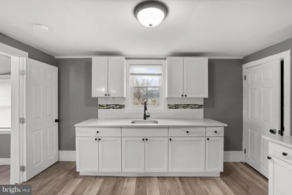 a kitchen with white cabinets and sink