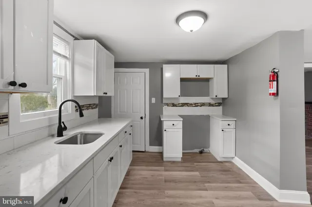 a kitchen with granite countertop a sink and a stove top oven with wooden floor