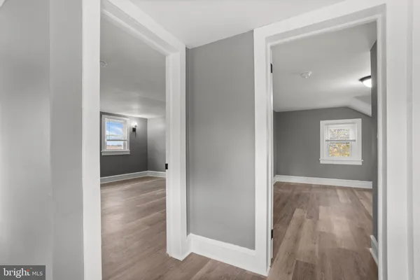 a view of a hallway with wooden floor and a bathroom