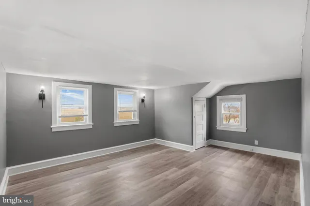 a view of an empty room with window and wooden floor