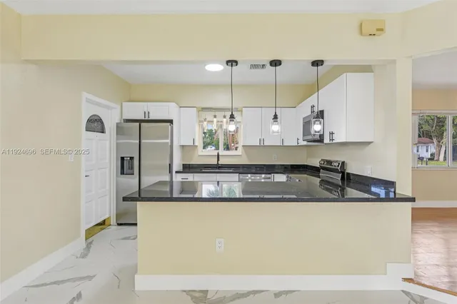 a large white kitchen with kitchen island granite countertop a sink and a refrigerator