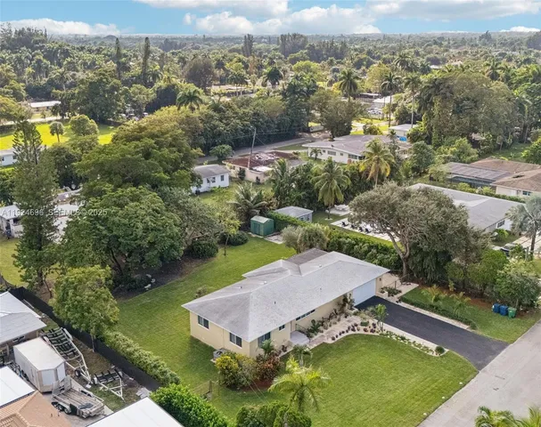 an aerial view of residential houses with outdoor space and trees