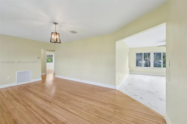 a view of an empty room with window and wooden floor