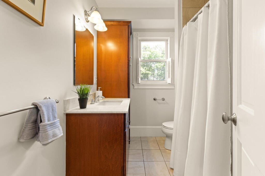 22 Fletcher Street, Unit 22 Winchester, MA 01890 - Photo 17 of 31 a bathroom with a granite countertop sink a toilet and a mirror