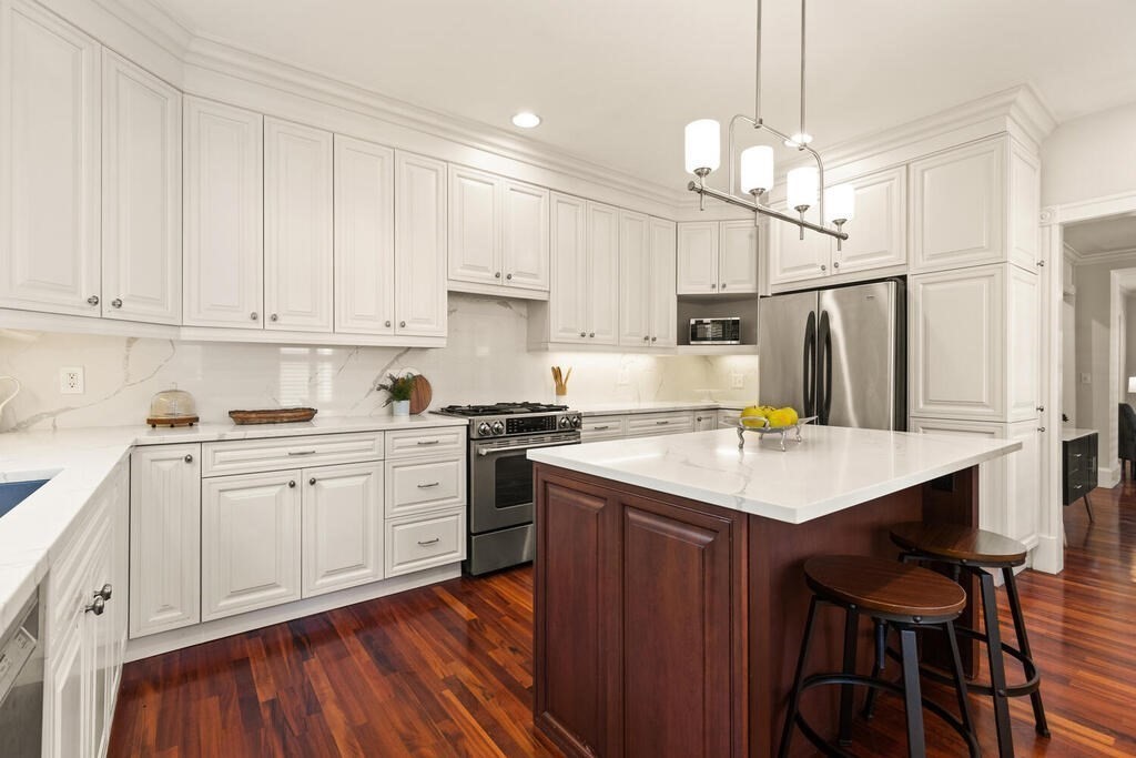 22 Fletcher Street, Unit 22 Winchester, MA 01890 - Photo 9 of 31 a kitchen with kitchen island a sink a stove a refrigerator and white cabinets with wooden floor
