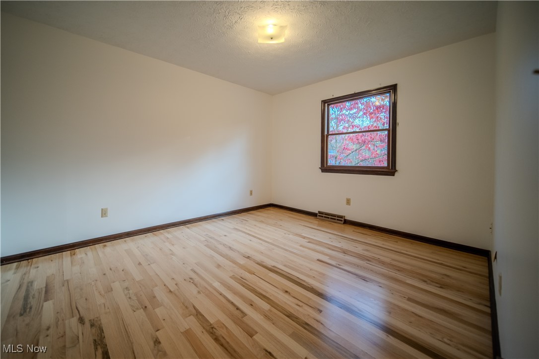 698 Albert Horning Road Atwater, OH 44201 - Photo 32 of 40 Empty room with light wood-style flooring and a textured ceiling