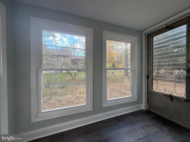 a view of an empty room with wooden floor and windows
